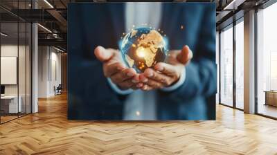 Businessperson holding a glowing, digital earth symbolizing global connection, innovation, and technology in a corporate setting. Wall mural