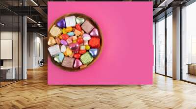 Bowl of candies, top view photo of bowl of candies. Colorful sweets in the wooden plate. Isolated pink background, copy space for greetings. Wrapped luxury chocolate. Ramadan feast celebration concept Wall mural