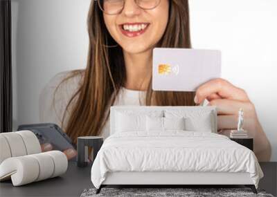 Showing credit card, happy young brunette girl showing credit card. Portrait of Caucasian woman holding mobile phone. Isolated white background, copy space. Online shopping concept idea, advertisement Wall mural