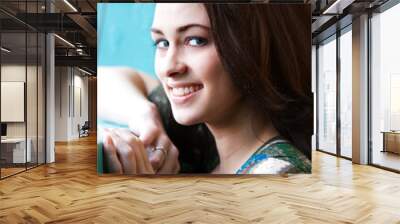 Closeup portrait of a young woman resting her arm on a windowsill. Vertical shot. Wall mural