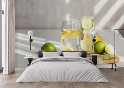 two glasses of water with lemon and lime on a wooden board and a flower of narcissus  Wall mural