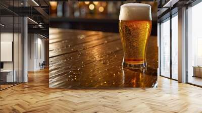 A pint glass of cold fresh beer with cap of foam on a bar table. A chill atmosphere.	 Wall mural