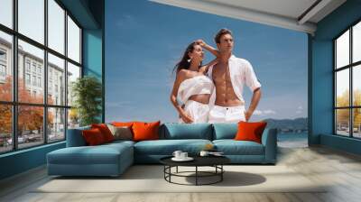 Fashion photo of a beautiful  fitness happy couple in white clothes in love standing  and posing on the beach. Phuket. Thailand Wall mural