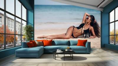 long-haired brunette Asian appearance lies and sunbathes on the beach. Tropical weekend. Wall mural