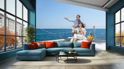 Loving couple admires the sea and drink champagne from glasses. Romantic cruise on a sailing yacht. Wall mural