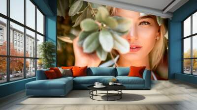 Portrait of a blonde with natural beauty among the leaves of tropical trees. Spa and pleasure Wall mural