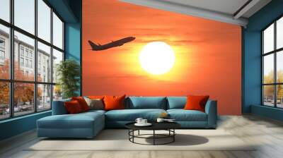 Plane flying against a bright sunset Wall mural