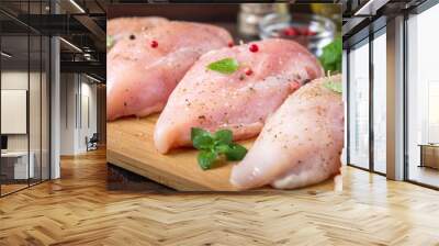 Raw chicken fillets on a cutting board against the background of a wooden table. Meat ingredients for cooking. Wall mural