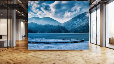 Beautiful lakeshore with mountains and a cloudy blue sky in the backgroun perfect for wallpapers Wall mural