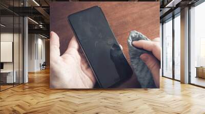 Cleaning A Smartphone Screen Of Dust, Dirt And Fingerprints With A Cleaning Wipe Over A Table Wall mural