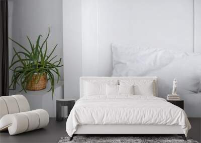 Bedroom interior with white bed and big green indoor flower. White clean bedroom with ready for sleep bed. Wall mural