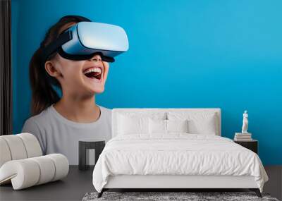 Young girl getting experience using VR headset glasses isolated on a blue background with copy space Wall mural