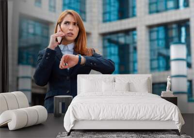 Angry business woman talking on the phone and looking at the wristwatch Wall mural