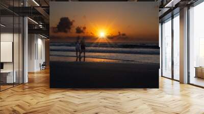 Two women enjoying walking along beach at sunrise Wall mural