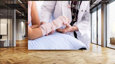 Bone specialist doctor examining serious injured woman at her arm with splint and bandage. Physician doctor talking to broken arm woman patient in the hospital. Healing in injured person concept. Wall mural