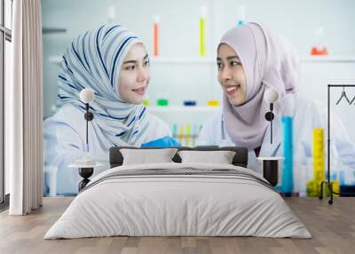 Happy Asian muslim scientist student investigating a chemistry together in laboratory. Two intelligence Muslim chemistry researcher examining and testing for pharmaceutical chemistry. Bio tech concept Wall mural