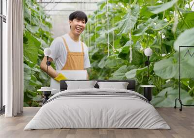 Happy cheerful Asian watermelon farm worker inspecting an agricultural product quality. Asian male farmer using laptop to collecting - analyzing farming data. Wall mural