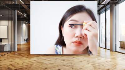 Portrait of beautiful Asian woman using eyelash brushing her eyes close up on white background. Wall mural