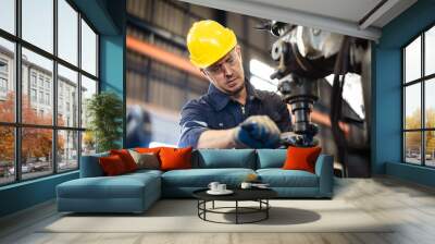 Professional caucasian white ethnicity male technician operating the heavy duty machine in the lathing factory. Technician in safety and helmet suit controlling a machine in factory. Wall mural