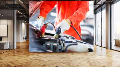 Professional roadside technician support using an emergency jump start cable to connect a battery from other car to the one which out of battery. Wall mural