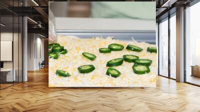 Hand laying out jalapeno, cheddar cheese for pan pizza. Wall mural