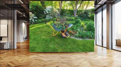 Wheelbarrow on a perfect green lawn in a cultivated country garden used for garden work. Professional gardening service or contracted gardener maintaining a lush backyard and planting seasonal shrubs Wall mural