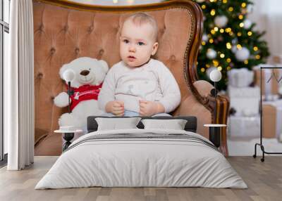 christmas concept - cute little baby girl sitting on vintage sofa near decorated christmas tree Wall mural