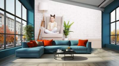 cute preteen girl sitting in armchair over white brick wall Wall mural