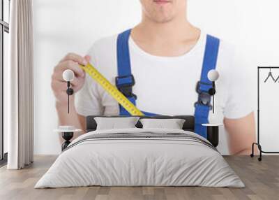 man builder in blue coveralls holding measure tape isolated on w Wall mural