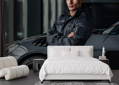 Man in mechanic uniform posing with modern black sport car Wall mural