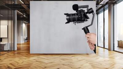 modern dslr camera on 3-axis gimbal stabilizer with follow focus system in male videographer hands over gray background Wall mural