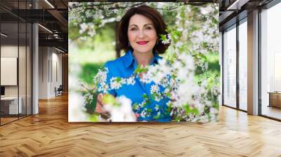 portrait of middle aged woman in summer garden with blooming che Wall mural