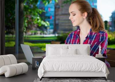 teenage girl sitting with laptop in park Wall mural