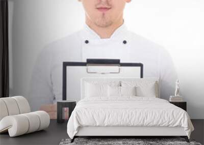 young man in chef uniform showing clipboard with blank paper iso Wall mural