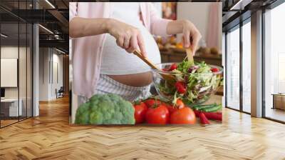 Pregnant Woman Mixing Fresh Green Salad On Kitchen. Closeup. Wall mural