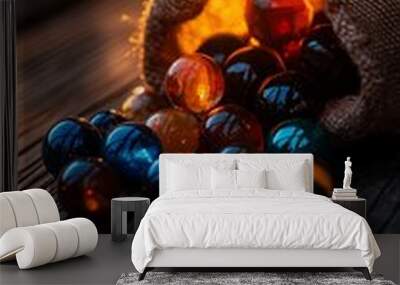 A burlap sack spills colorful glass marbles onto a wooden surface as the sun sets in the background. Wall mural