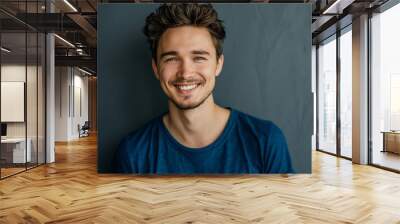 Close up portrait of young smiling handsome guy in blue t-shirt isolated on grey background Wall mural