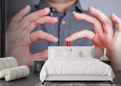 Man's hands close-up holding red and blue pills Wall mural