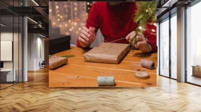 Man wrapping Christmas present at home with blurred lights on the background Wall mural