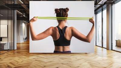 Young athletic woman doing exercises with fitness rubber band Wall mural