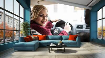 Confident and beautiful. Rear view of attractive young woman in casual wear looking over her shoulder while driving a car Wall mural