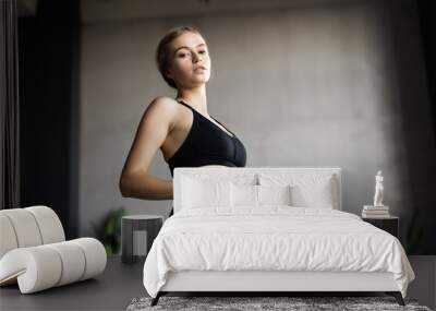 Fitness woman exercising and stretching arms at home in the living room in sportswear. Wall mural