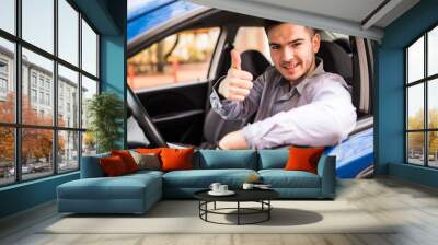 Happy smiling man sitting inside car showing thumbs up. Handsome guy excited about his new vehicle. Positive face expression Wall mural