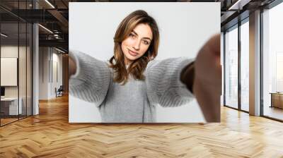 Portrait of a young attractive woman making selfie photo on smartphone isolated on a gray background Wall mural