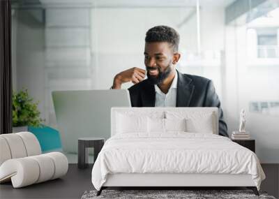 Portrait of handsome African black young business man working on laptop at office desk Wall mural