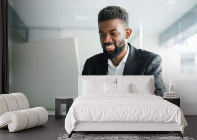 Portrait of young African man typing on laptop in office Wall mural