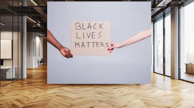 protest white and black hands holding cardboard poster with message text BLACK LIVES MATTERS isolated on white background.  Wall mural