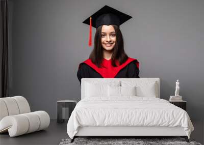 Studio portrait of funny excited joyful student girl with graduation certificate. Happy academy, college or university graduate standing against gray background, holding diploma and smiling at camera Wall mural