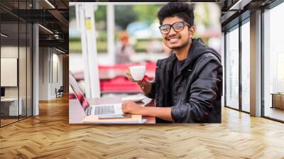 Young Asian indian man sitting in coffeeshop table and working on laptop Wall mural