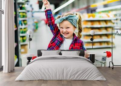 Young happy baby sitting in shopping trolley in hypermarkt Wall mural